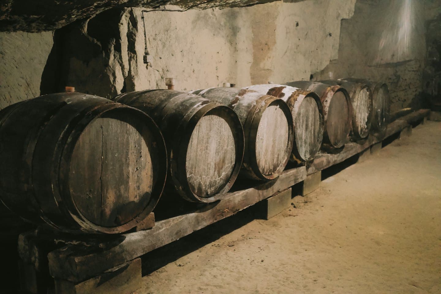 Sei botti di vino in legno si trovano all'interno di una cantina in pietra.