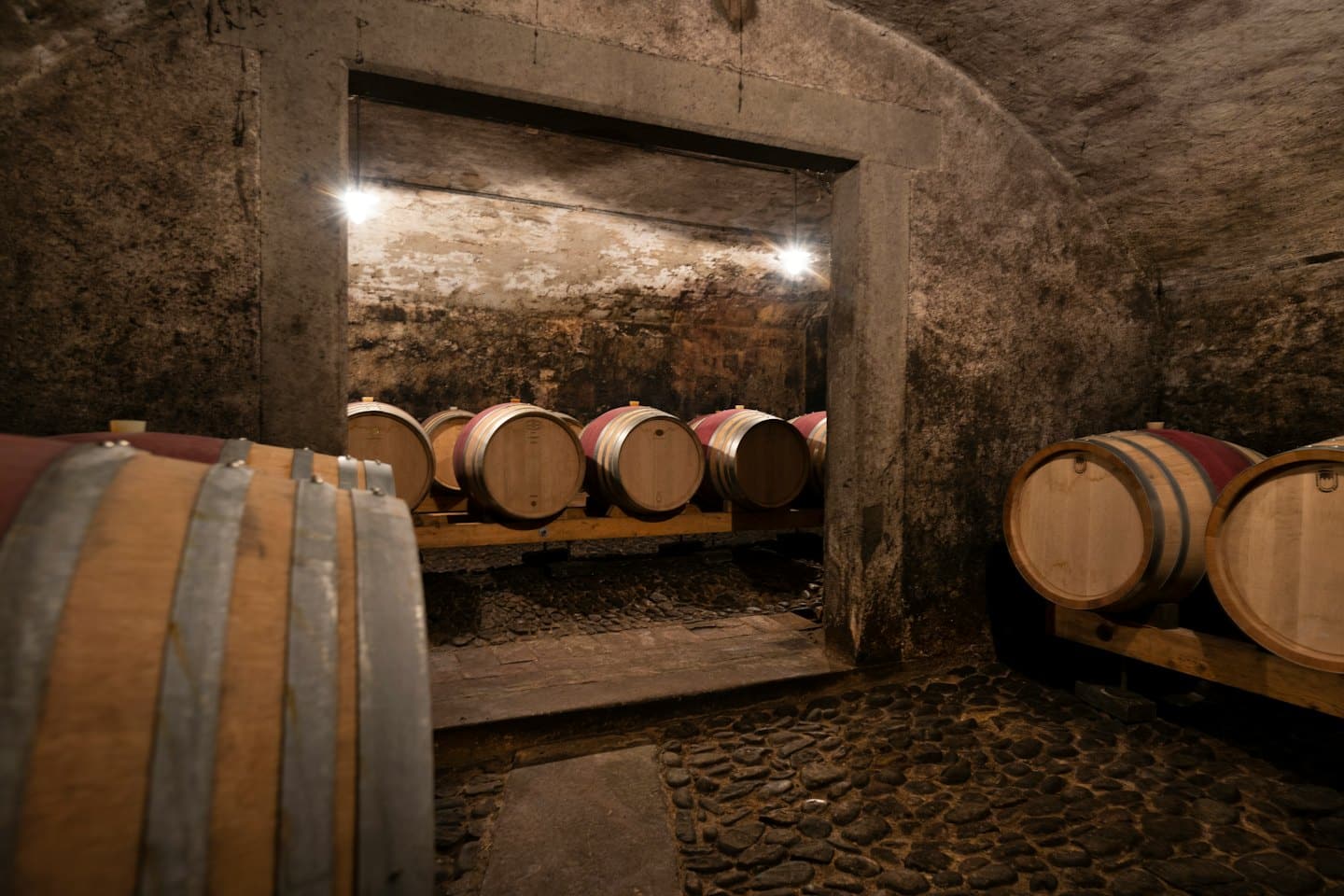 Botti di vino in legno sono conservate in una cantina a volta in pietra.